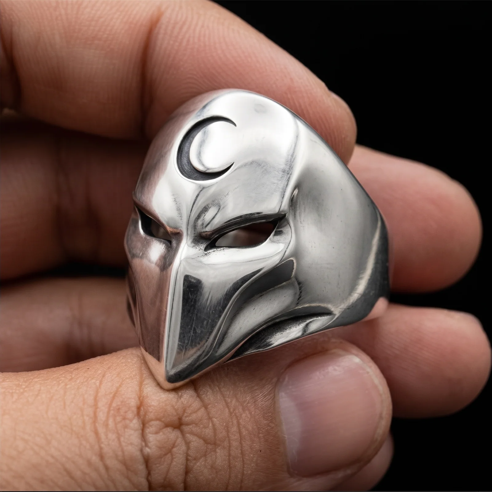 Long pointed mask ring held from the left side with smooth cheek planes and heavy band visible