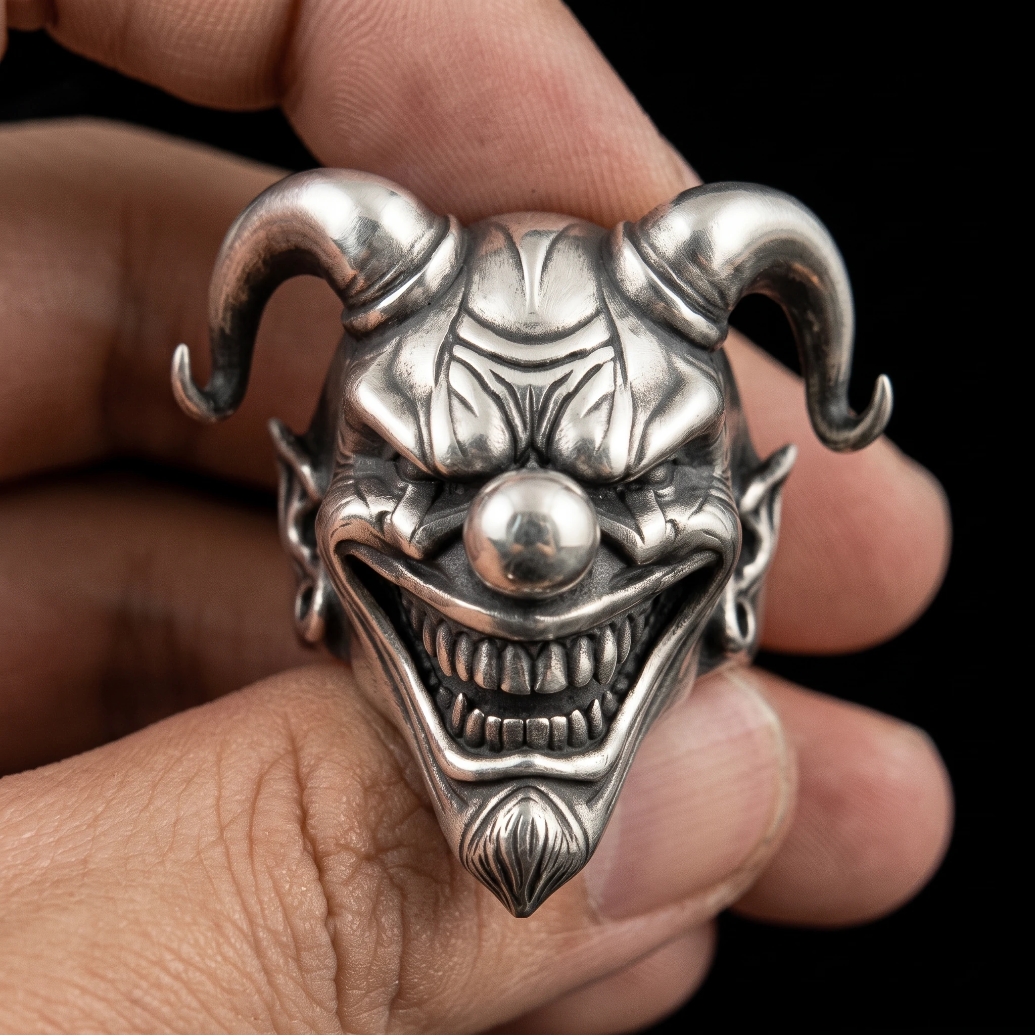 Horned jester face ring held in front view