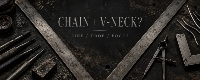 V-neck necklace placement represented by V-shaped steel rulers, dividers, gravers and raw silver wire on a dark workshop bench