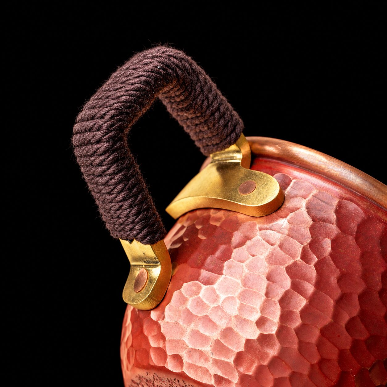 Close view of the copper cup cord-wrapped handle and warm-toned fittings on black